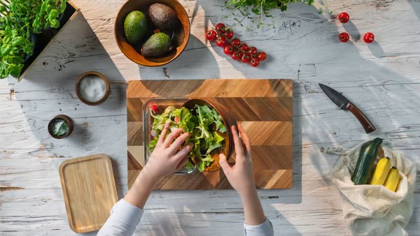 Hands preparing a fresh salad on a wooden board